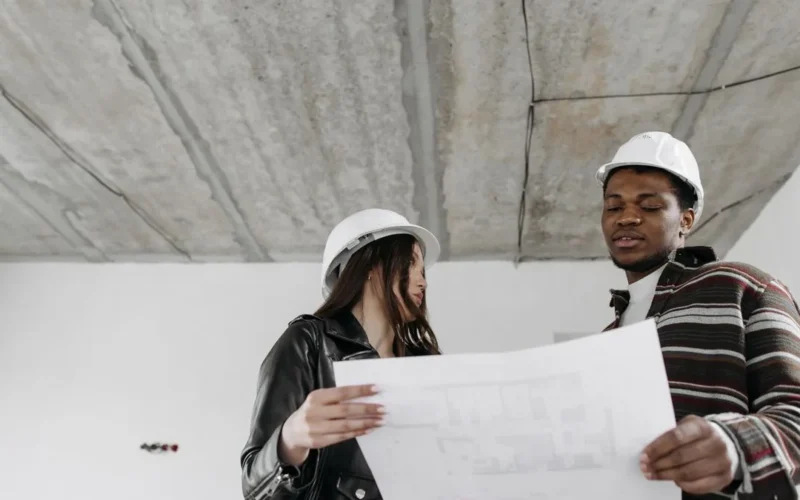 Profesionales con casco revisando planos en obra