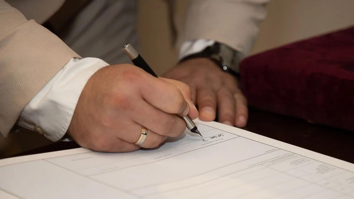 Firma de documento de compraventa de un inmueble sobre un escritorio